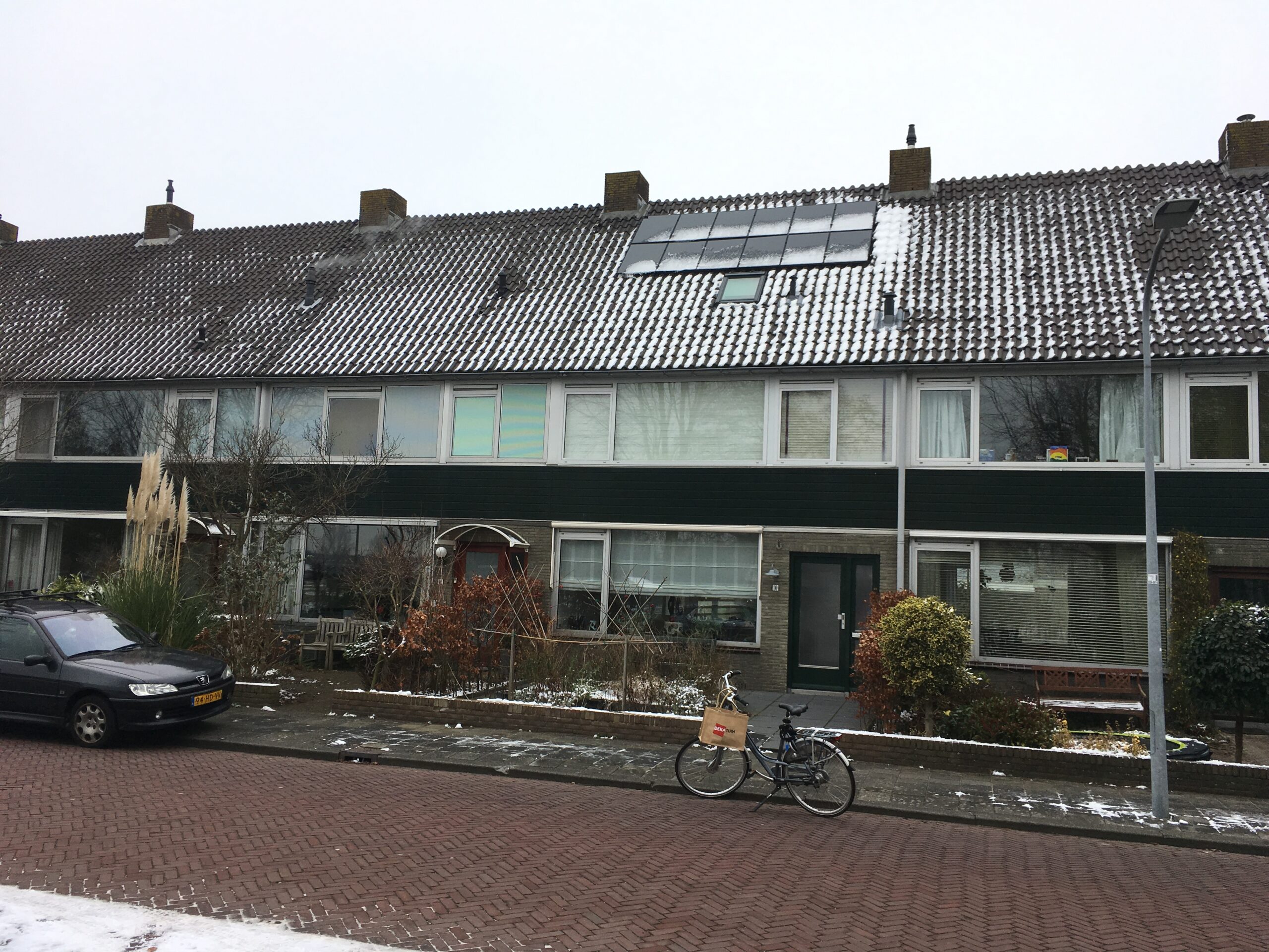Rij woningen in het Ramplaankwartier met PVT-panelen op een besneeuwd pannendak.