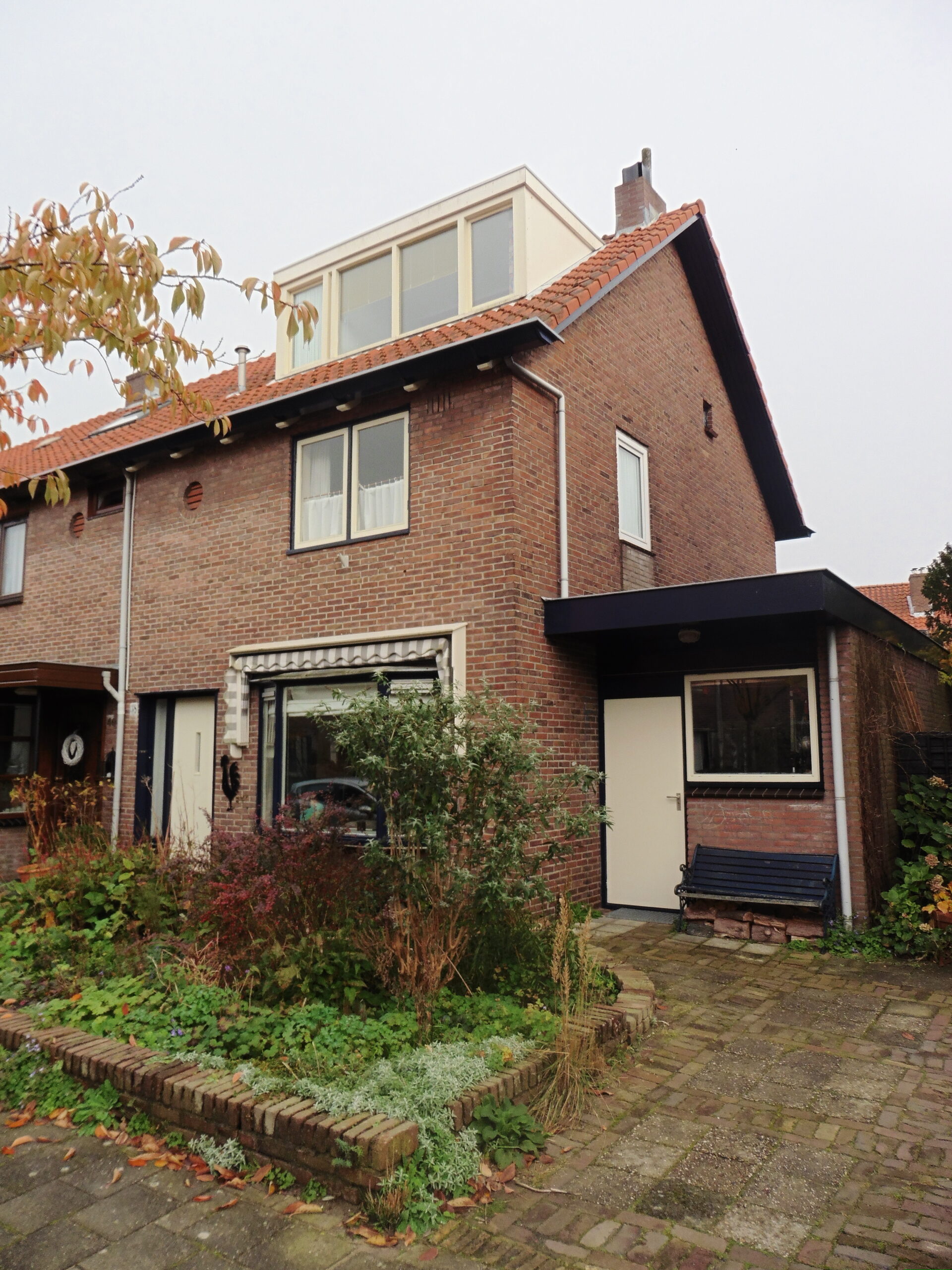 Vrijstaande bakstenen woning in het Ramplaankwartier met pannendak en voortuin in de herfst.
