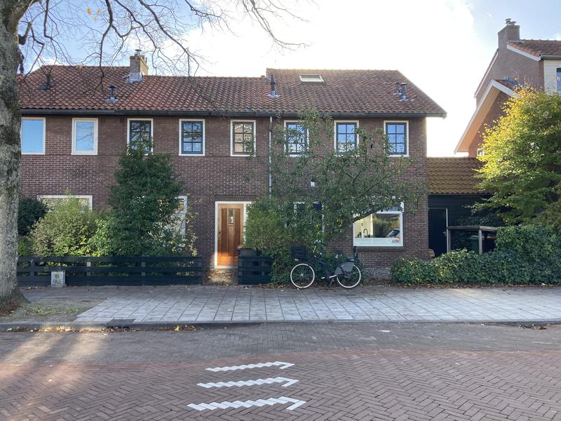 Een rij bakstenen woningen in het Ramplaankwartier met een fiets voor de deur op een zonnige dag.