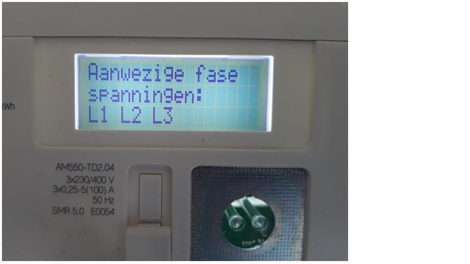 Display van een slimme meter met de tekst 'Aanwezige fase spanningen: L1 L2 L3', met daaronder het typeplaatje waarop 3 x 230/400 V staat.